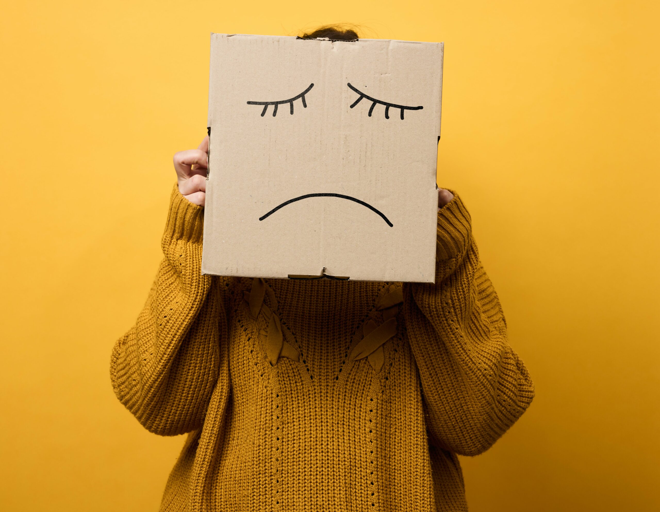 person holding cardboard of sad face